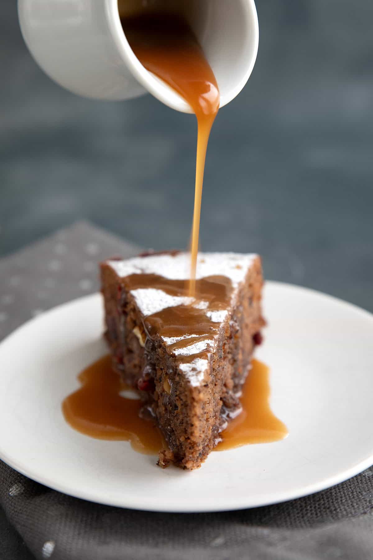 Caramel sauce being drizzled over a slice of keto fruitcake.