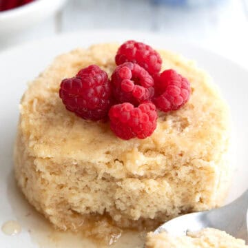 Keto Mug Pancake on a white plate with raspberries on top.