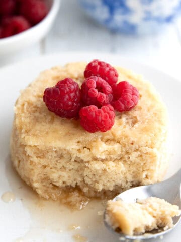 Keto Mug Pancake on a white plate with raspberries on top.