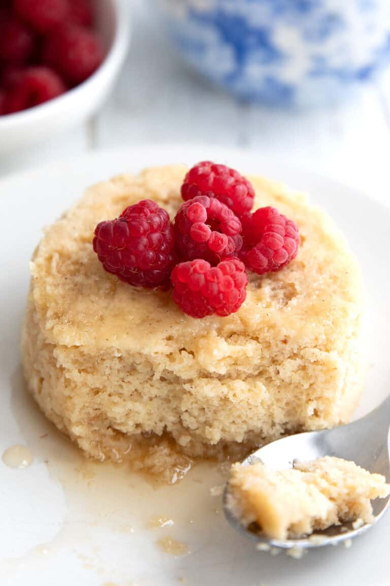 Keto Mug Pancake on a white plate with raspberries on top.