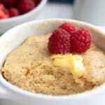 Titled image of Pancake in a Mug in a white ramekin with fresh raspberries.