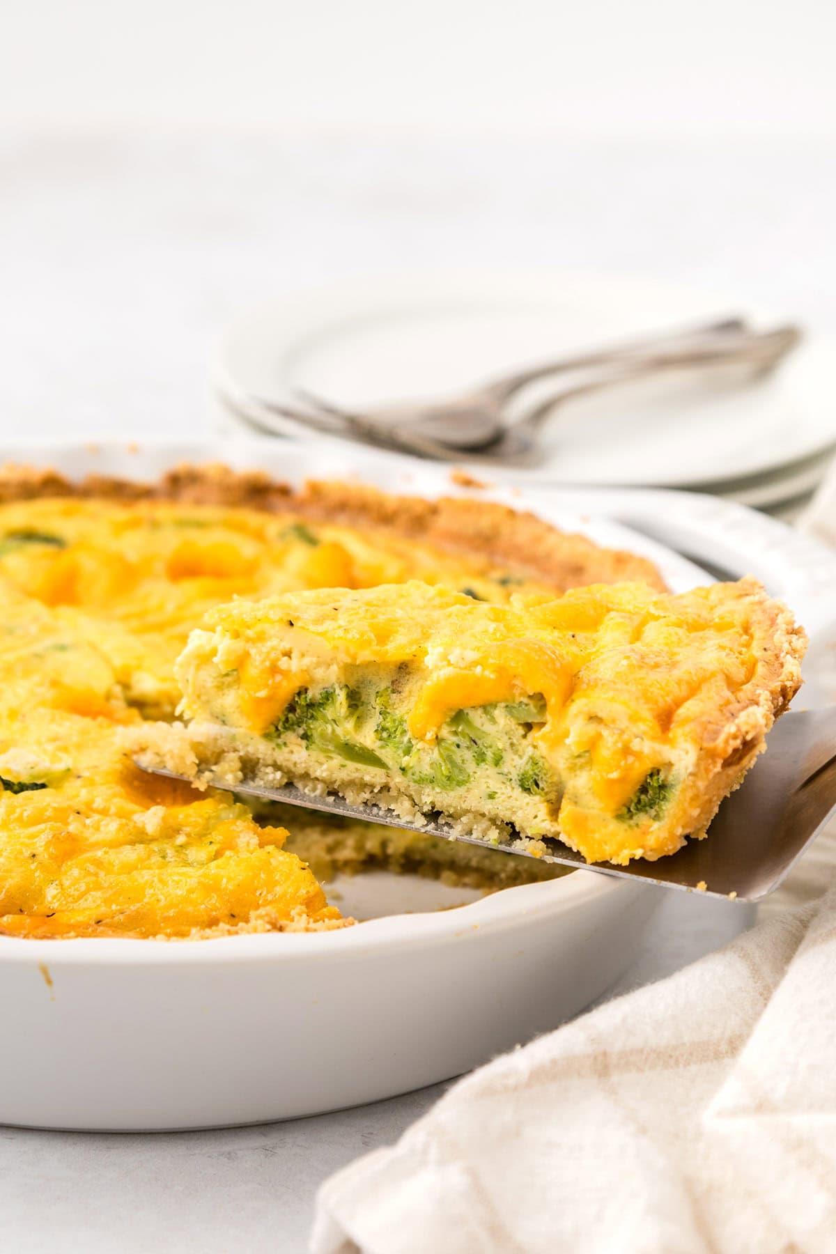 A white plate filled with keto quiche, with a slice being lifted out.