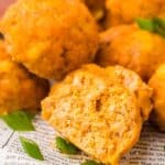 Title image close up of Buffalo Chicken Meatballs piled up on a white plate with a bite taken out of one.