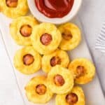 Titled image top down view of a white platter filled with keto corn dog bites and a bowl of sugar-free ketchup.