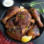 A black bowl filled with Air Fryer Tandoori Chicken on a black tabletop, with a red patterned napkin.