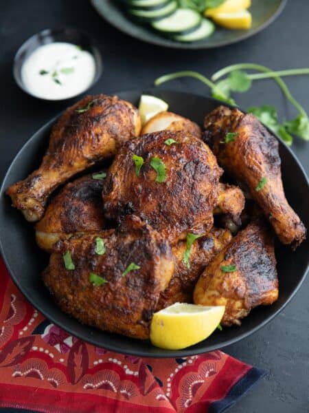 A black bowl filled with Air Fryer Tandoori Chicken on a black tabletop, with a red patterned napkin.