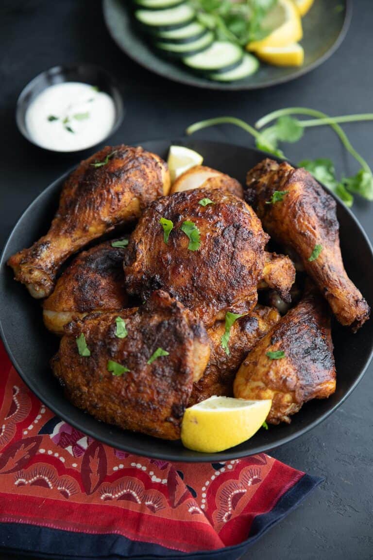 A black bowl filled with Air Fryer Tandoori Chicken on a black tabletop, with a red patterned napkin.