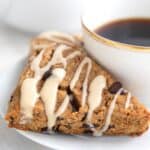 Titled image of a keto espresso scone on a white plate with a cup of coffee.