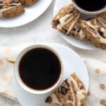 Top down image of Keto Espresso Scones on white plates with cups of coffee.