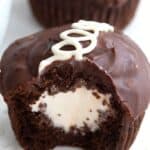 Close up shot of a cream filled chocolate cupcake with a bite taken out of it.