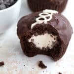 A copycat Keto Hostess Cupcake on a marble table top with a bite taken out of it and crumbs strewn around.