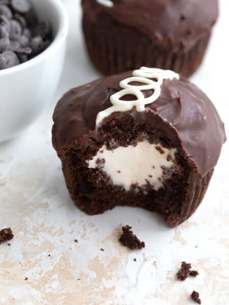 A copycat Keto Hostess Cupcake on a marble table top with a bite taken out of it and crumbs strewn around.