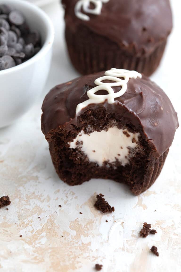 A copycat Keto Hostess Cupcake on a marble table top with a bite taken out of it and crumbs strewn around.