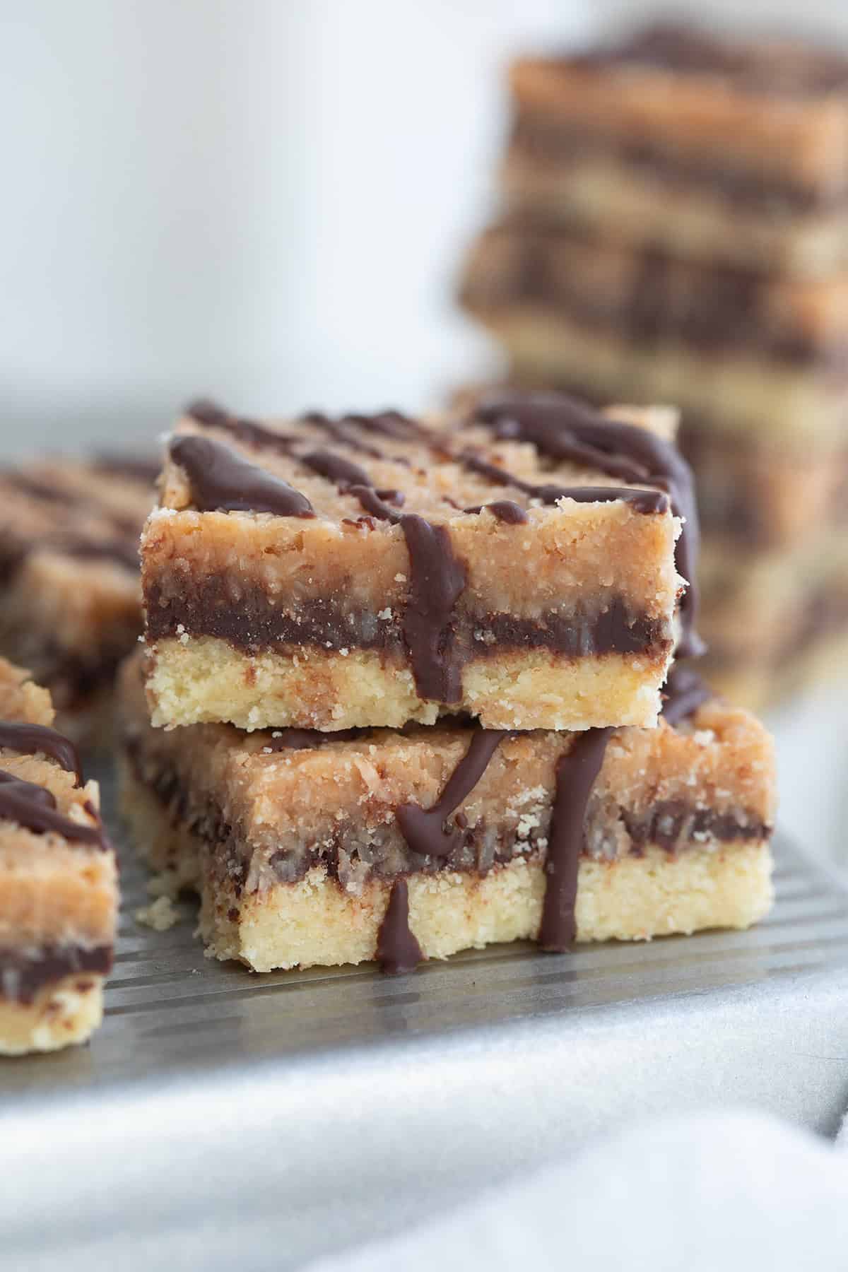 Two Keto Samoa Cookie Bars piled on a metal tray with more in the background.