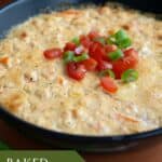 Close up shot of freshly baked shrimp dip with chopped tomatoes and green onion on top.