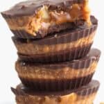 Titled Pinterest image of a stack of Keto Snickers Cups with a bite taken out of the top one.