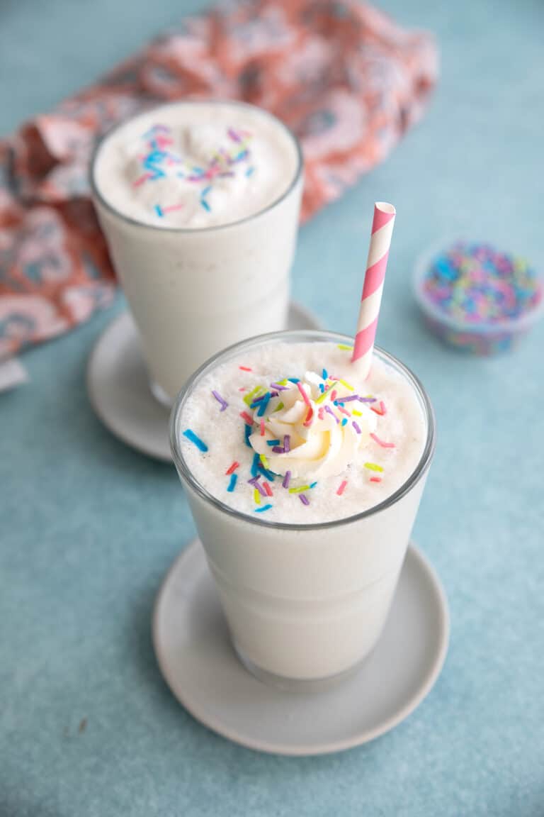 Two Keto Vanilla Protein Shakes on a teal table top.