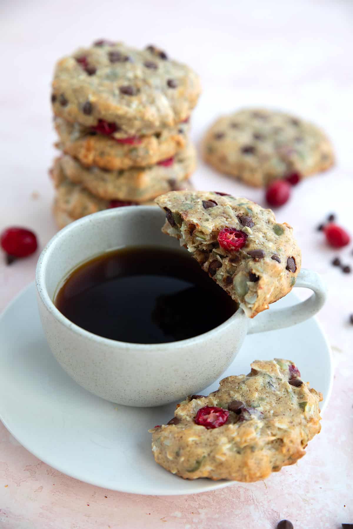 A Protein Breakfast Cookie broken in half with one part resting on a cup of coffee.