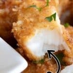 Titled image close up of crispy keto fish sticks with one broken open to shown the tender white fish inside.