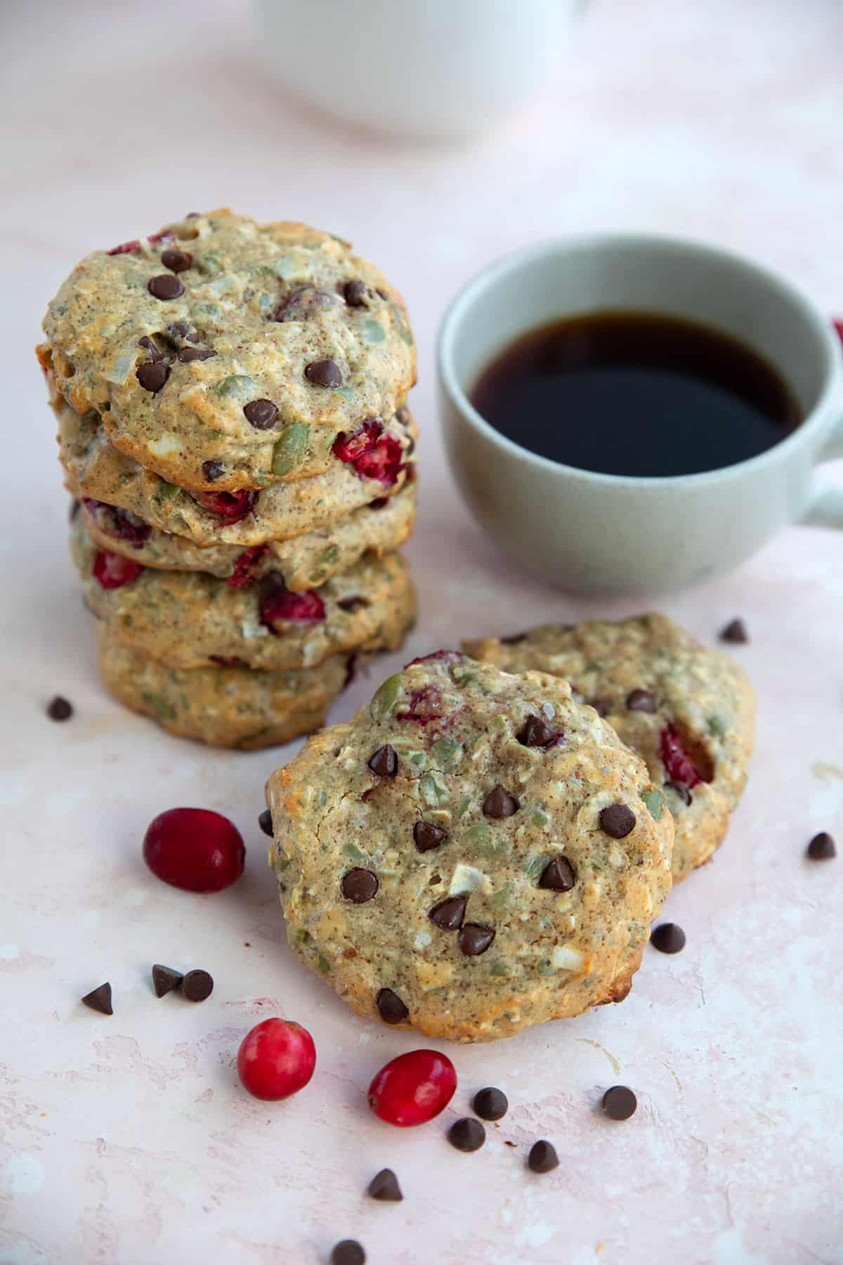 Protein Breakfast Cookies in a stack on a pink table with a cup of coffee.