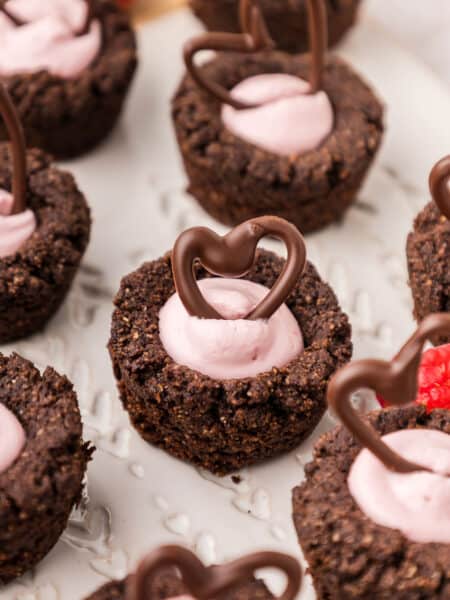 Close up shot of Keto Raspberry Cheesecake Cookie Cups on a white plate, with chocolate hearts on top.