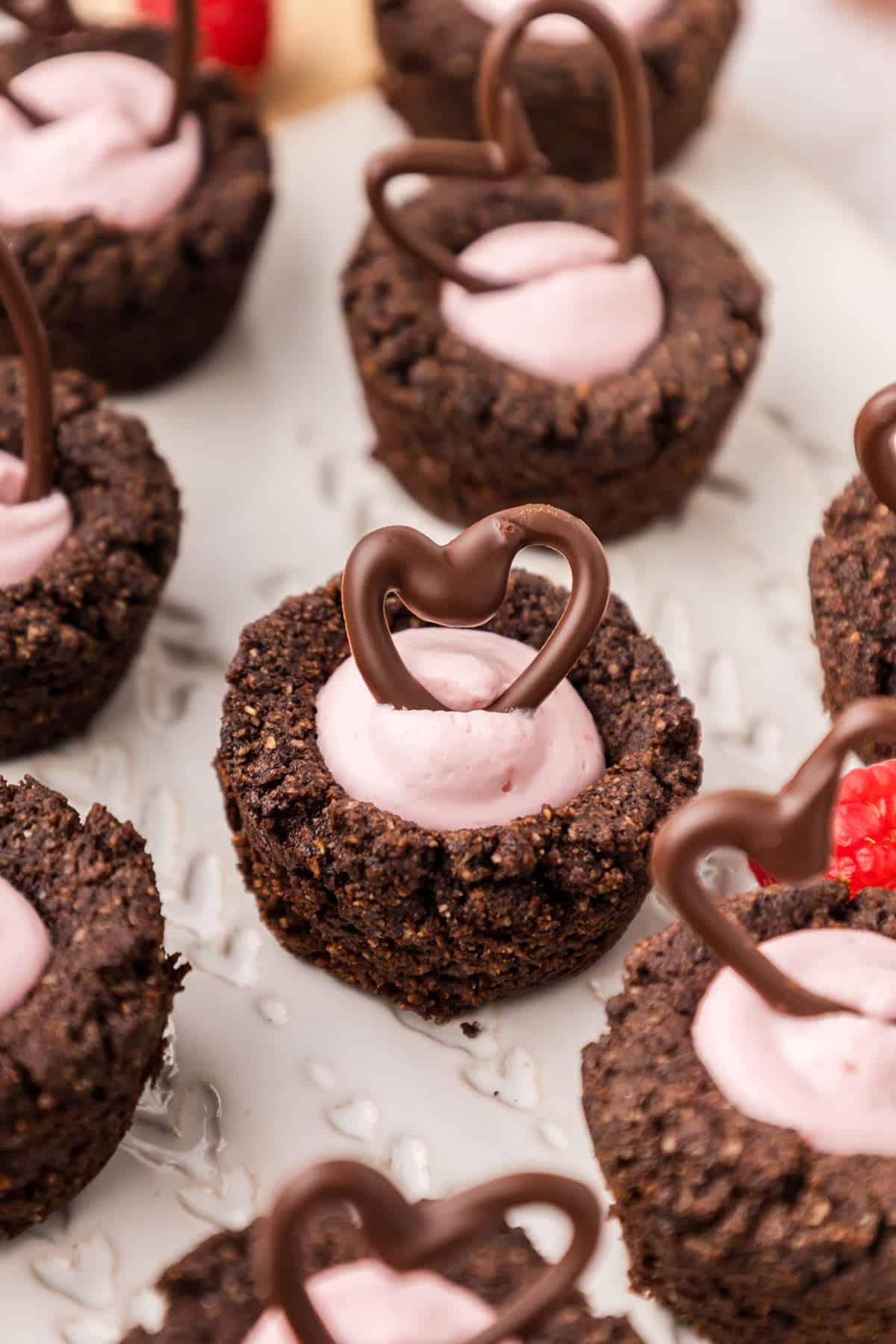 Close up shot of Keto Raspberry Cheesecake Cookie Cups on a white plate, with chocolate hearts on top.