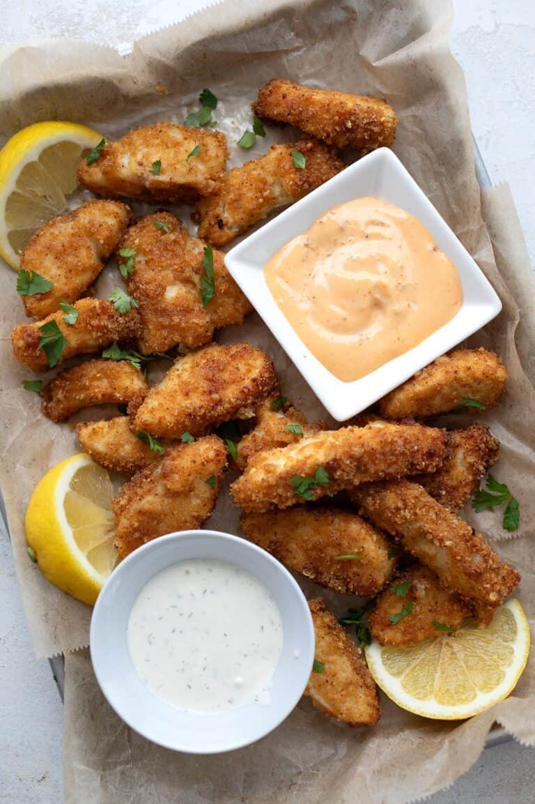 Top down image of air fryer fish sticks on a metal tray lined with parchment paper.