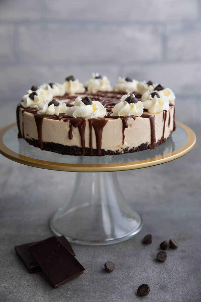 Keto Irish Cream Cheesecake on a glass cake stand rimmed with a gold edge.