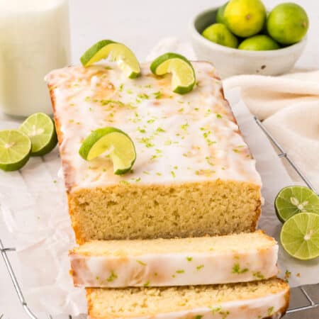 A loaf of Keto Key Lime Pound Cake on a wire cooling rack with several slices cut out in front.