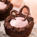 Close up shot of a Keto Raspberry Cheesecake Cookie Cups on a white plate with a chocolate heart on top.