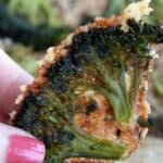 Titled image of a piece of Crispy Parmesan Smashed Broccoli being held up over the pan.