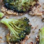 Titled image of smashed broccoli on a pan lined with parchment paper.