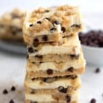 A stack of Keto Chocolate Chip Cookie Cheesecake Bars with a bite taken out of the top one.