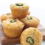 Keto Cheddar Jalapeno Muffins piled up on a wooden cutting board.