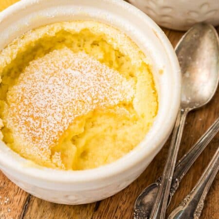 Close up shot of a Keto Lemon Pudding Cake in a white ramekin with a spoonful taken out of it.