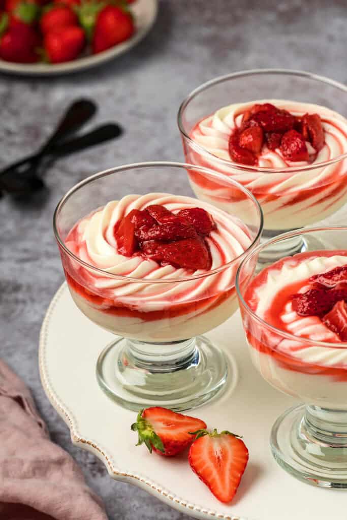 Three dessert glasses filled with mascarpone mousse on a white cake stand.
