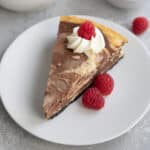 A slice of keto marble cheesecake on a white plate with raspberries.