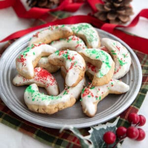 A metal plate filled with keto pecan crescent cookies over a plaid holiday napkin.