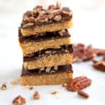 A stack of Keto Toffee Bars with pecans strewn around.