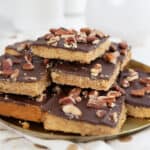Keto Toffee Cookie Bars piled up on a gold colored plate over a polka dot napkin.