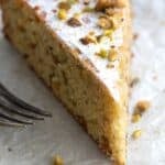 Titled image close up of a slice of Keto Pistachio Cake on a gold plate lined with parchment paper.
