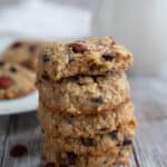Keto Oatmeal Cookies in a stack on a gray wooden table, with the top one broken open to show the texture inside.
