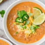 Top down image of Keto Taco Soup in a white bowl with cheese, avocado, and jalapeños on top.