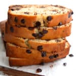 A stack of slices of Keto Chocolate Chip Loaf Cake on a white background with a breadknife in front.