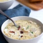 A white bowl filled with keto seafood chowder on a white wooden table.