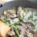 Titled image of a wooden spoon digging into Keto Philly Cheesesteak Skillet.