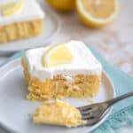 A slice of Keto Lemon Poke Cake on a white plate with several forkfuls taken out of it.