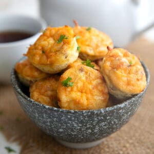 Sausage Egg and Cheese Bites piled up in a speckled gray bowl over a burlap napkin.