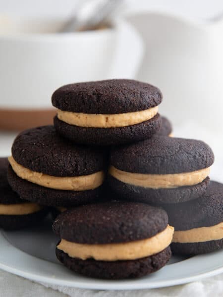 Keto Chocolate Peanut Butter Whoopie Pies piled up on a white plate over a white napkin.
