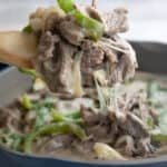 Close up shot of a wooden spoon lifting some Philly Cheesesteak Skillet out of the pan.
